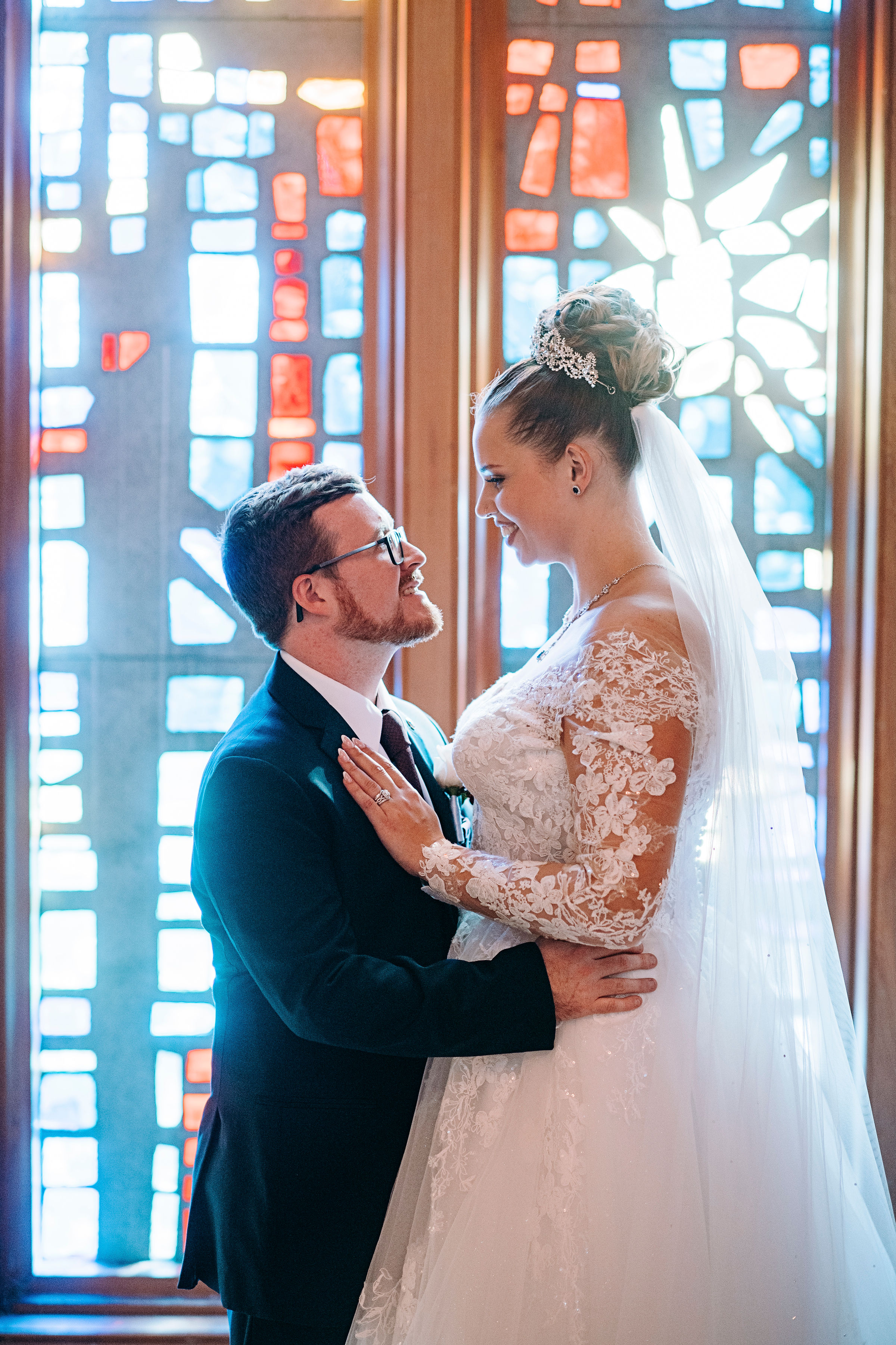 Wedding couple in front of stained glass of Norton Chapel