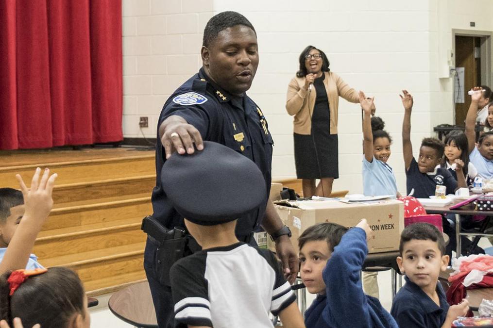 Mark Simmons places his police hat on the head of a student.