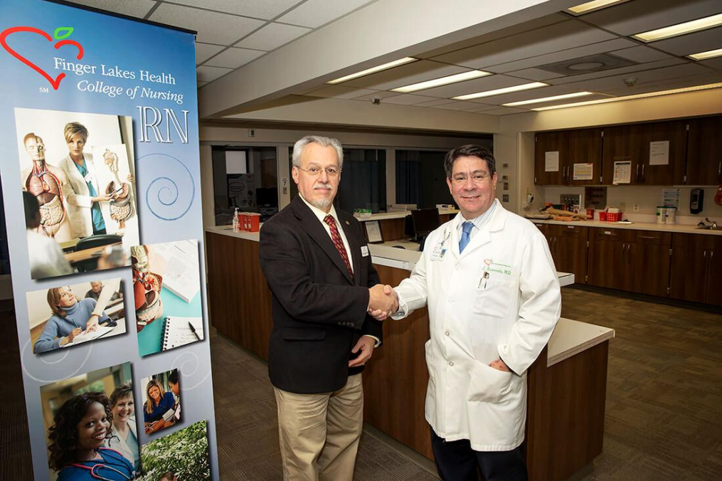 Keuka College President Jorge L. Díaz-Herrera, Ph.D., and Finger Lakes Health President &amp; CEO Jose Acevedo, M.D., M.B.A. shake hands in the Finger Lakes Health College of Nursing laboratory. 